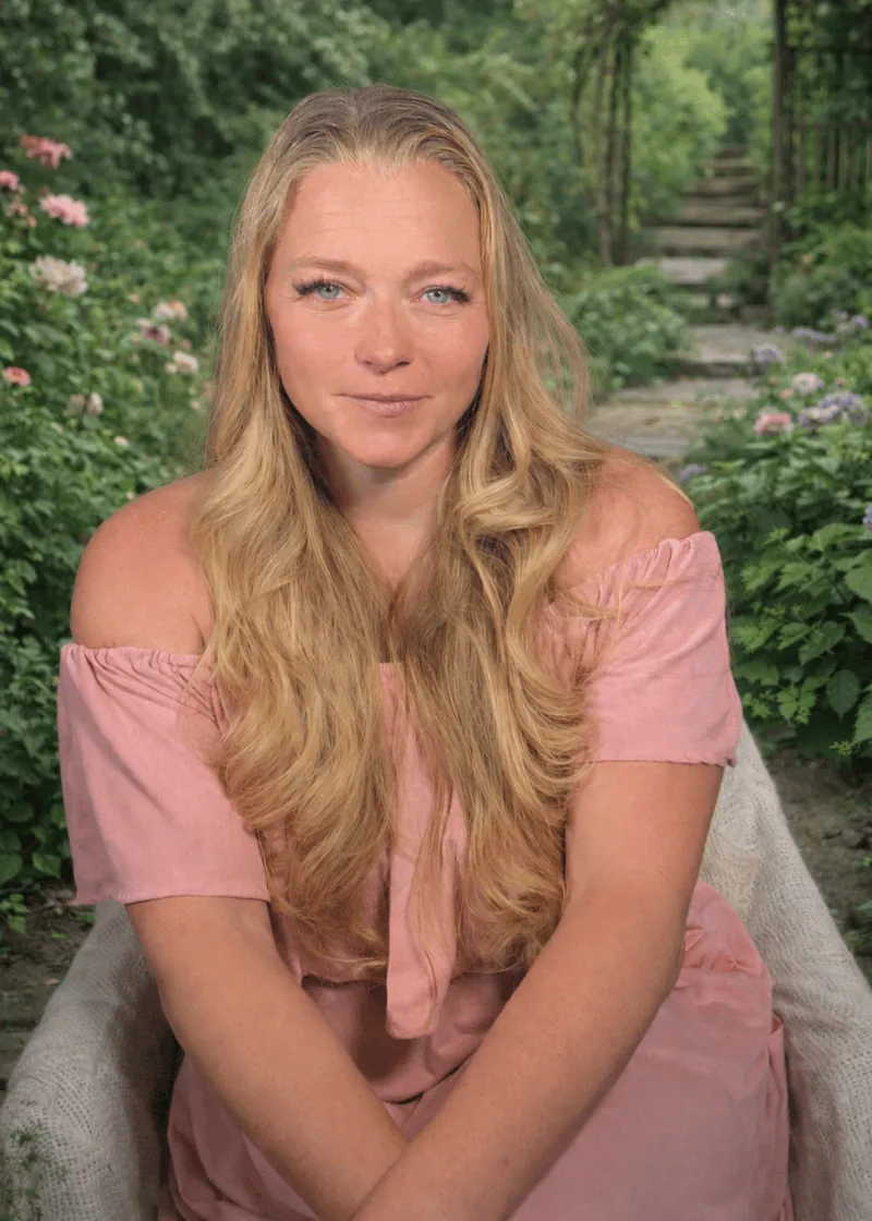 Laura Kunz, founder of The Temple of Her, in a soft pink dress in a garden